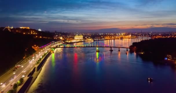 Nocny pejzaż. kolorowe świecące doprowadziły most przez rzekę i nabrzeże drogi w Kijowie — Wideo stockowe