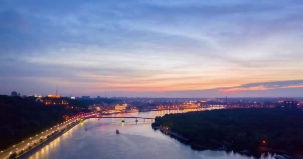 Nachtbild. Bunt leuchtende Brücke über Fluss und Uferstraße in Kiew — Stockvideo