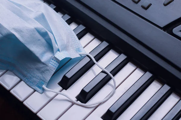 Medical mask on the keys of the piano, background, toned