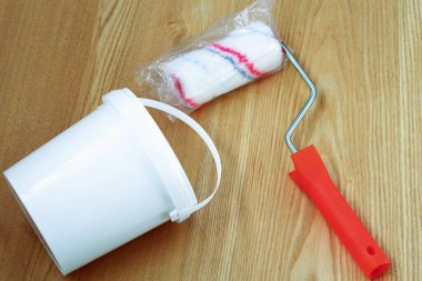 Boya ve silindirli plastik kova ahşap bir arka planda yatıyor.