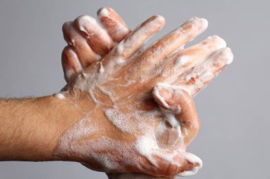 Açık gri banyo arka planında erkek sabunlu eller. Hijyen kavramı