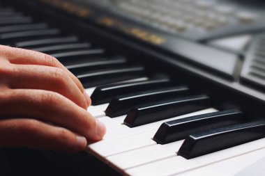 Müzisyen eli bir sentezleyicinin anahtarında, arka planda, tonlanmış