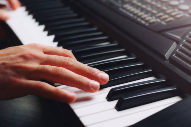 Müzisyen eli bir sentezleyicinin anahtarında, arka planda, tonlanmış