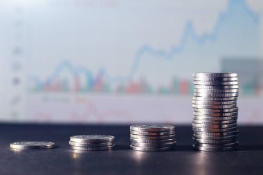 Hisse senedi tablosunun bulanık arkaplanındaki madeni paralar, artan bir eğilim