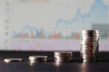 Hisse senedi tablosunun bulanık arkaplanındaki madeni paralar, artan bir eğilim