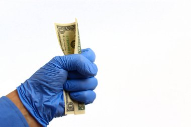 Tıbbi eldivendeki bir el beyaz arka planda bir dolar tutar, izole edilmiş. Dünya krizi konsepti