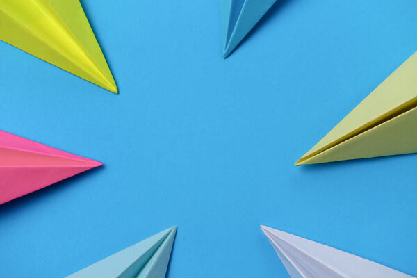 Multicolored noses of paper airplanes on a blue background with place for text.