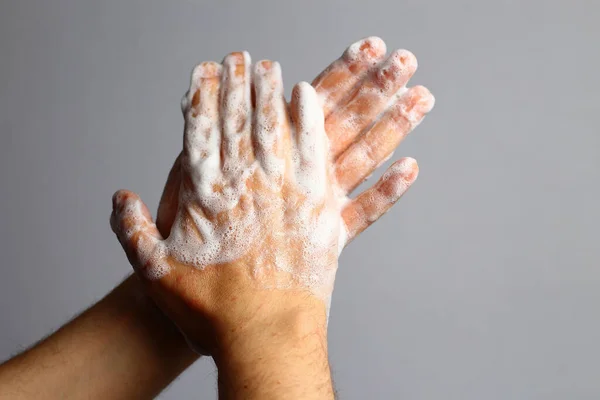Male soaped hands on a light gray bathroom background. Hygiene concept