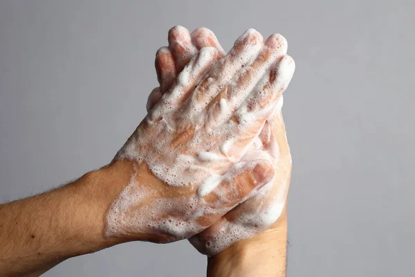 Male soaped hands on a light gray bathroom background. Hygiene concept