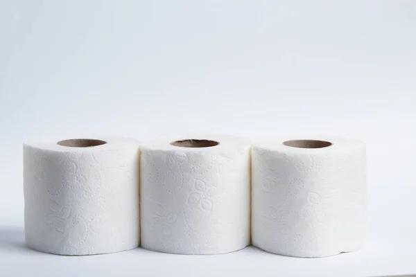 Three rolls of toilet paper on a light background