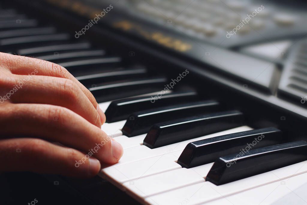 Musician's hand on the keys of a synthesizer, background, toned