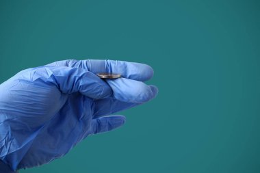 Tıbbi eldivenli bir doktor, Marrs Green 'in arka planına bozuk para atıyor. Seçimin sembolü