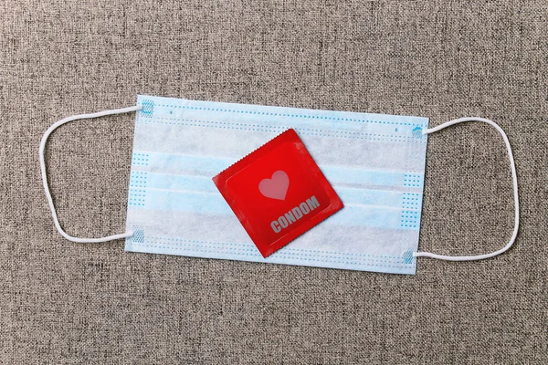 Condom on a medical surgical mask. Bed background