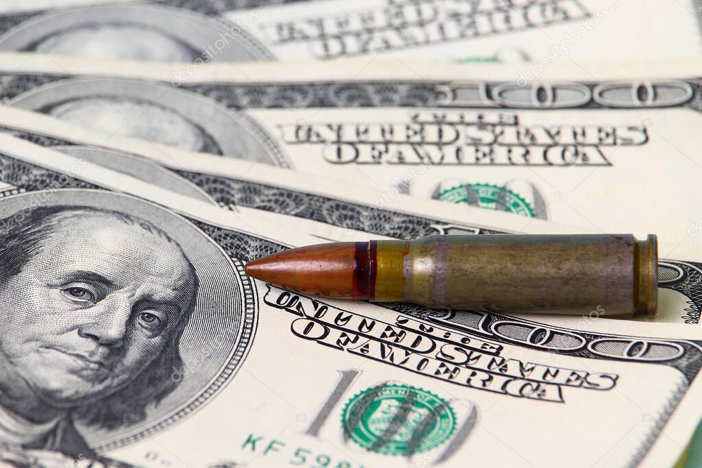 Military bullet lies on the background of US dollars