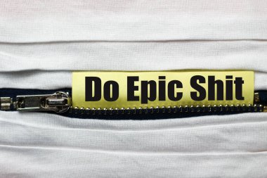 White fabric with zipper close-up. Sticker with text or caption Do epic shit