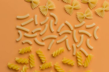 Turuncu arka planda farklı türde makarna.