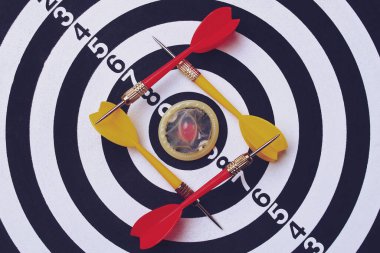 Dart tahtası hedef dartlarının arka planında açılmamış prezervatif sesi