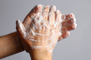 Açık gri banyo arka planında erkek sabunlu eller. Hijyen kavramı