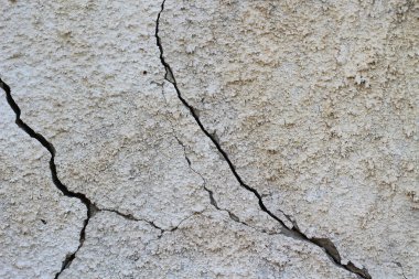 Çatlamış beton doku arka planı. Çatlakları olan gri yüzey. Bir sürü parçalanmış alçı parçası. Ayrılma, anlaşmazlık, anlaşmazlık, anlaşmazlık gibi soyut kavramlar. Gölgelerle güneşli bir gün.