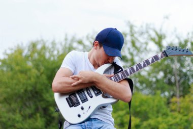 Gülümseyen adam gri gitaristleri öpüyor genç adam.