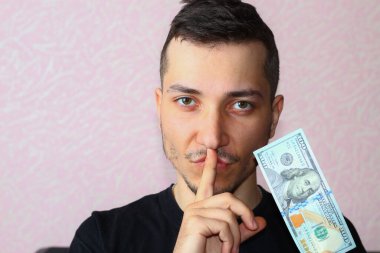 Genç adam sembolik olarak ağzını kapatıyor. Para için sessizlik kavramı.