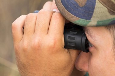 Asker dürbünle bakıyor genç adam.