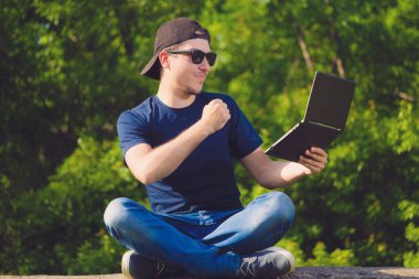 Genç serbest çalışan dizüstü bilgisayarı ve yumruğu tutuyor. Hedefe ulaşmanın sembolü.