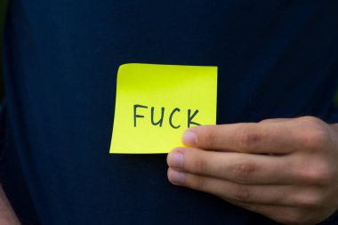 FUCK sticker in male hand with copy space for text or lettering.