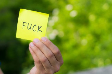 FUCK sticker in male hand with copy space for text or lettering.