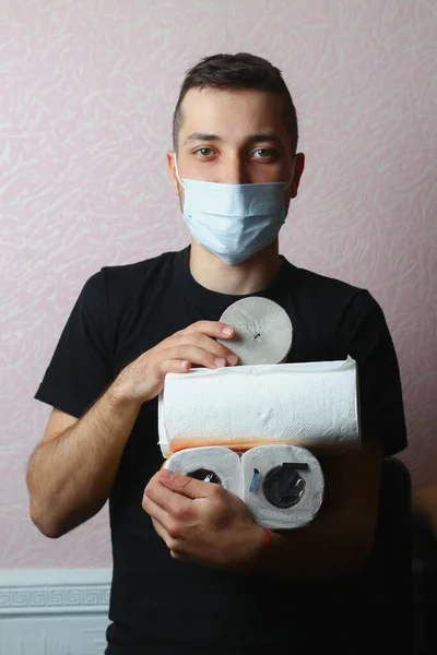Young man in a medical mask with toilet paper in his hands