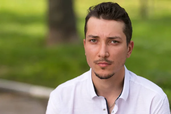 Bulanık bir geçmişi olan, beyaz gömlekli, üzgün ve çaresiz bir adam. Yakın plan portre.