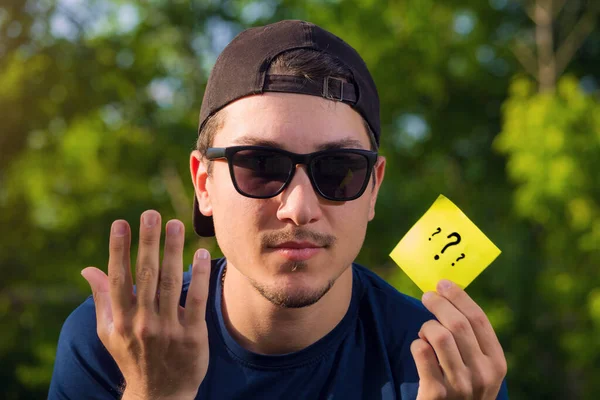 Ung Man Håller Handen Ett Klistermärke Med Tre Frågetecken Suddig — Stockfoto