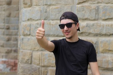 Mutlu ve neşeli bir adam bulanık bir arka planda klasik bir dokuma duvarında el kol hareketi yapıyor.