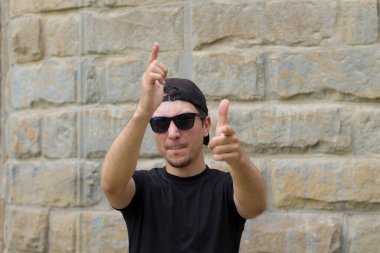 Mutlu ve neşeli bir adam bulanık bir arka planda klasik bir dokuma duvarında el kol hareketi yapıyor.