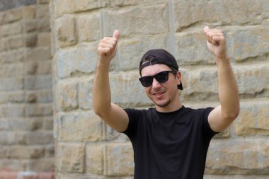 Mutlu ve neşeli bir adam bulanık bir arka planda klasik bir dokuma duvarında el kol hareketi yapıyor.