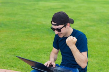 Yeşil çimlerde dizüstü bilgisayarı olan serbest çalışan biri..