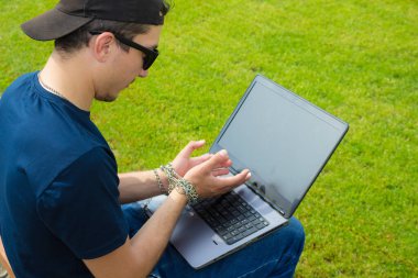 Elleri zincirli, dizüstü bilgisayarı olan, kaslı bir adam. Cihazlara, sosyal ağlara ve internete bağımlılık kavramı, bağlılık ve şefkat, uzak çalışma özgürlüğü tuzağı.
