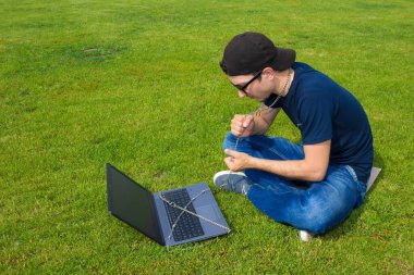 Metal bir zincirle dizüstü bilgisayara bağlanmış bir adam. Cihazlara, sosyal ağlara ve internete bağımlılık kavramı, bağlılık ve şefkat, uzak çalışma özgürlüğü tuzağı.
