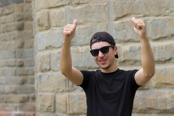 Mutlu ve neşeli bir adam bulanık bir arka planda klasik bir dokuma duvarında el kol hareketi yapıyor.