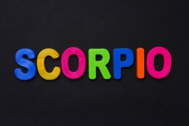 Akrep metni. Siyah dramatik bir arkaplanda parlak renkli neşeli harflerle yazılmış Zodiac yazısı. Alçakgönüllü. Burç TemasıComment