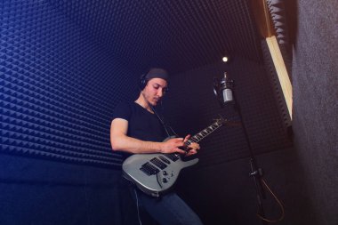 Bir kayıt stüdyosunda gitar çalan erkek müzisyen,