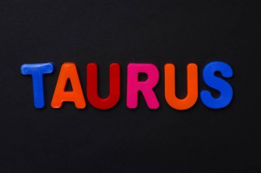 Boğa metni. Siyah dramatik bir arkaplanda parlak renkli neşeli harflerle yazılmış Zodiac yazısı. Alçakgönüllü. Burç TemasıComment