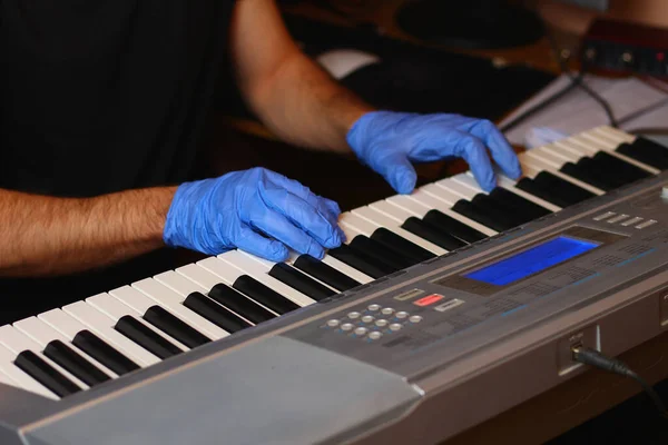 A musician plays with gloves on a musical instrument in an audio studio. The life of a pianist in the realities of Covid-19 pandemic.