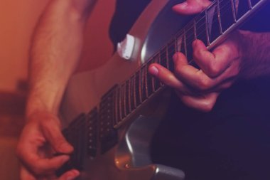 Müzik stüdyosunun karanlığında gitar çalan yakışıklı, yaratıcı bir adam.