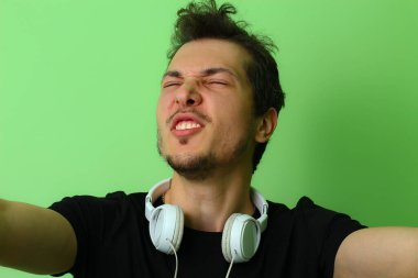 Açık yeşil duvar arka planında genç bir adam ya da adam. Mutluluk hissi.