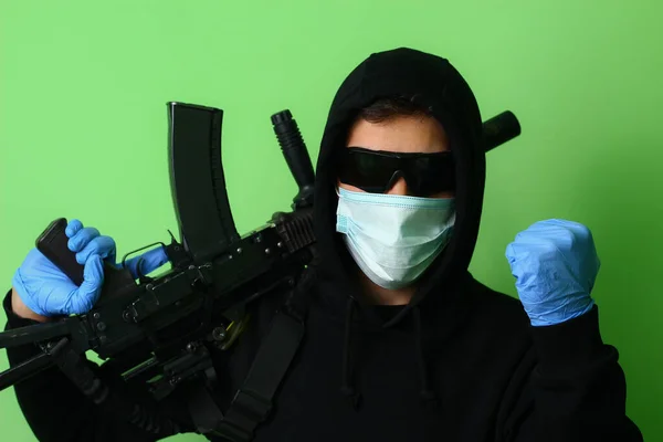 若い男性ギャングや医療外科マスクやフード付きの黒い服に身を包んだサングラスで犯罪者は 自動攻撃兵器を保持しています — ストック写真