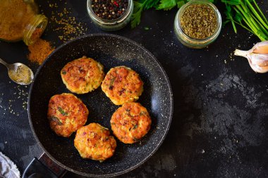 Tavada kızarmış köfte. Koyu beton bir masa arkasında tavuklu pirzola. Üst Manzara. Malzemeler ve pişmiş köfteler. Baharat, maydanoz, et yemeği..