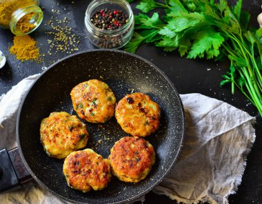 Tavada kızarmış köfte. Koyu beton bir masa arkasında tavuklu pirzola. Üst Manzara. Malzemeler ve pişmiş köfteler. Baharat, maydanoz, et yemeği..