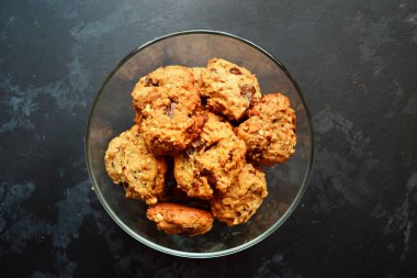 Çikolatalı yulaflı kurabiye. Siyah masa arka planında kurabiyeler, izole edilmiş. Üst görünüm.
