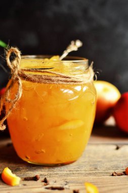 Portakal aromalı ev yapımı elma reçeli. Koyu bir arka planda, tahta bir masada cam bir kavanozda sıkıştım..